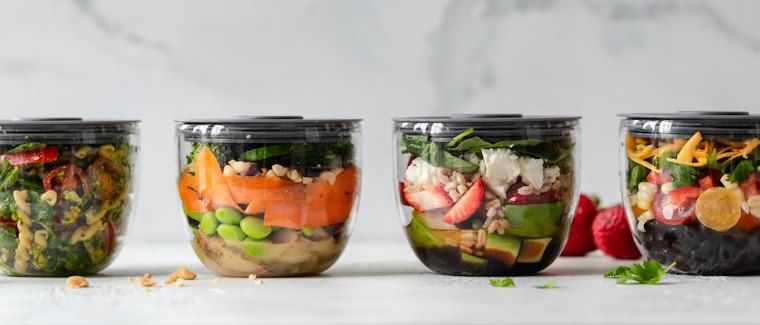 Four containers of fresh vegetables portioned for the week.